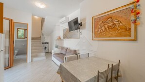 Un interior moderno con comedor, escalera y televisor montado.