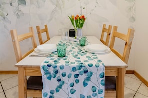 A dining table set with chairs, a vase with flowers, and a tablecloth with a leaf pattern.