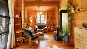 A cozy log cabin interior with a fireplace, wooden furniture, and a large window. - Holiday Home 'Hüssli Numero 1' with Private Terrace, Shared Garden and Wi-Fi (Hayingen)