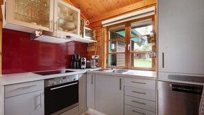 A kitchen with a stove, oven, dishwasher, and a window with a view of the outdoors. - Holiday Home 'Hüssli Numero 1' with Private Terrace, Shared Garden and Wi-Fi (Hayingen)