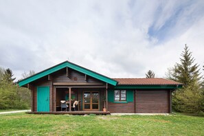 A wooden cabin with a porch, a sliding glass door, and a small outdoor seating area. - Holiday Home 'Hüssli Numero 1' with Private Terrace, Shared Garden and Wi-Fi (Hayingen)