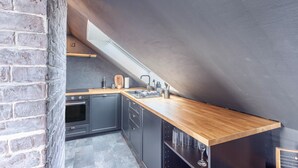 A compact kitchen with a wooden countertop, built-in oven, and a skylight.