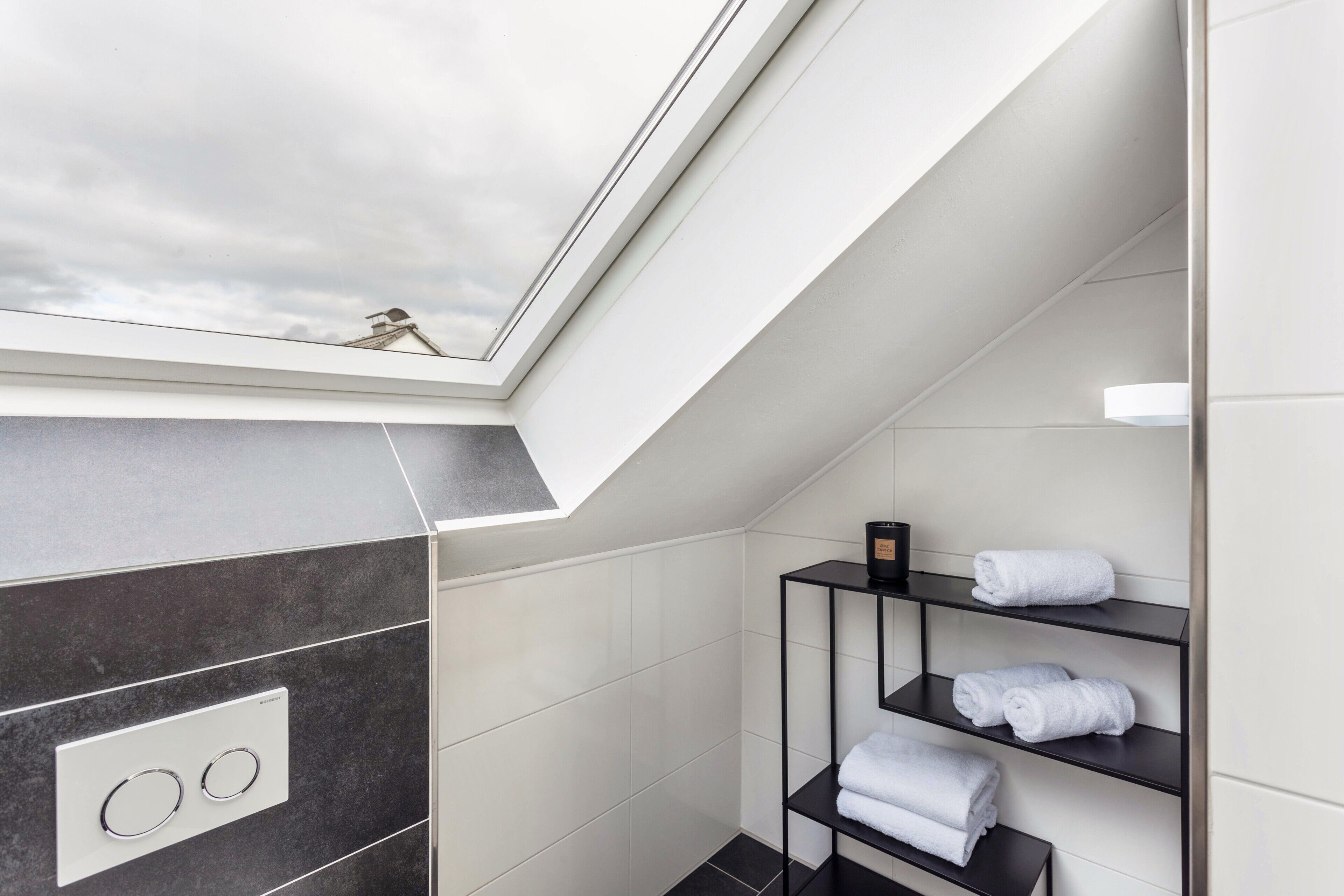 Une salle de bain moderne dotée d’un puits de lumière, d’un porte-serviettes et d’un panneau de commande.