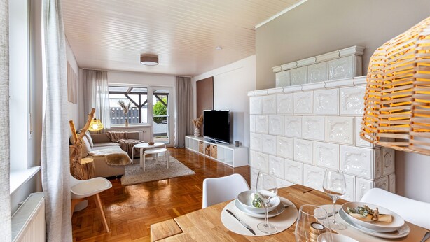 Ein modernes Wohnzimmer mit einem Holzesstisch, weißen Möbeln und einem Fernseher.