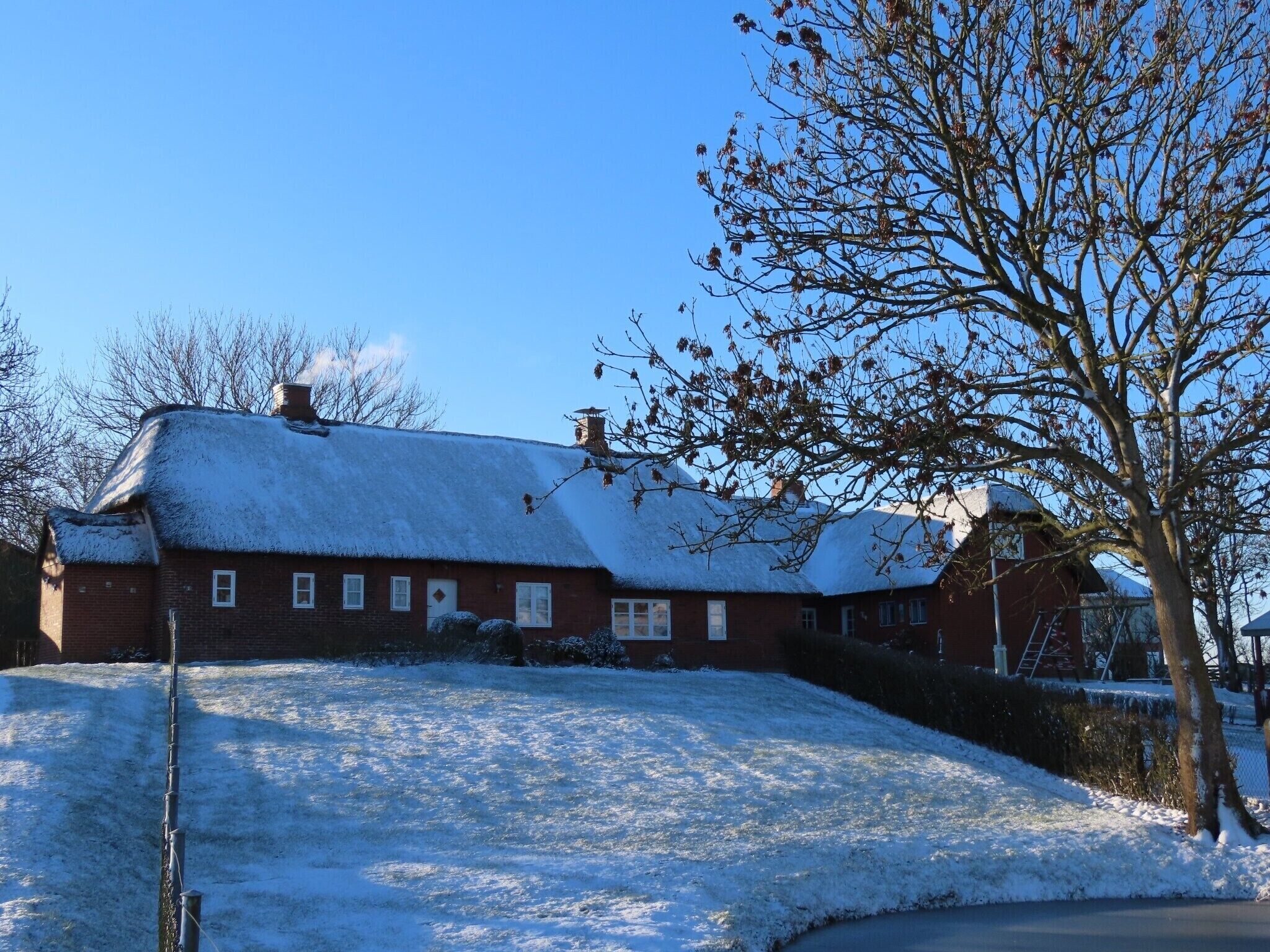 A snow-covered house with a sloped roof and a chimney.