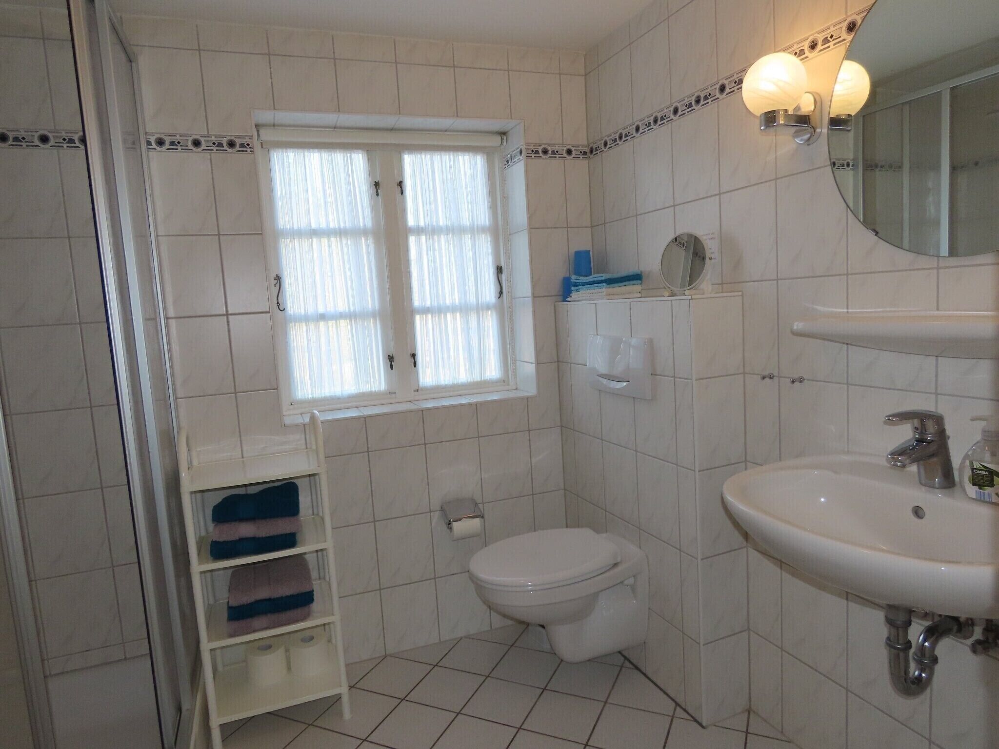A bathroom with a toilet, sink, and window.