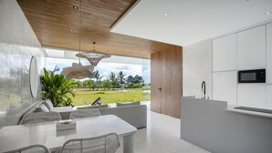 A modern kitchen with white cabinetry, a built-in microwave, and a large window overlooking a green landscape.
