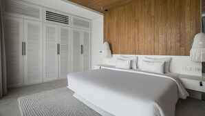 A modern bedroom with a large bed, wooden panel wall, white wardrobe, and a hanging lamp.