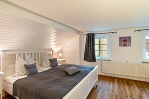 A bedroom with a bed, bedside tables, a radiator, a window with curtains, and a wall-mounted picture. - Holiday Apartment "Schwarzwaldtani – Städtle 3" in Bühl (Bühl)