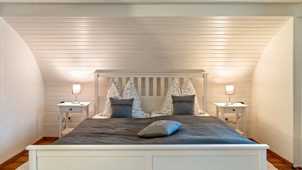 Un dormitorio con una cama, dos mesitas de noche y un cabecero.
