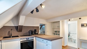 Una cocina moderna con horno integrado, un lavamanos y una encimera de madera.