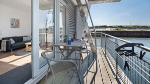 A modern deck with a table and chairs, overlooking a body of water. - Houseboat 'Sutje' with Sea View, Private Terrace and Wi-Fi (Großenbrode)