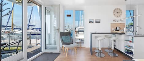 Una cocina moderna con vista a barcos, un comedor con taburetes de bar y un ventanal grande.