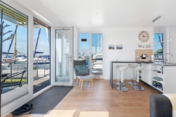A modern kitchen with a view of boats, a dining area with bar stools, and a large window.