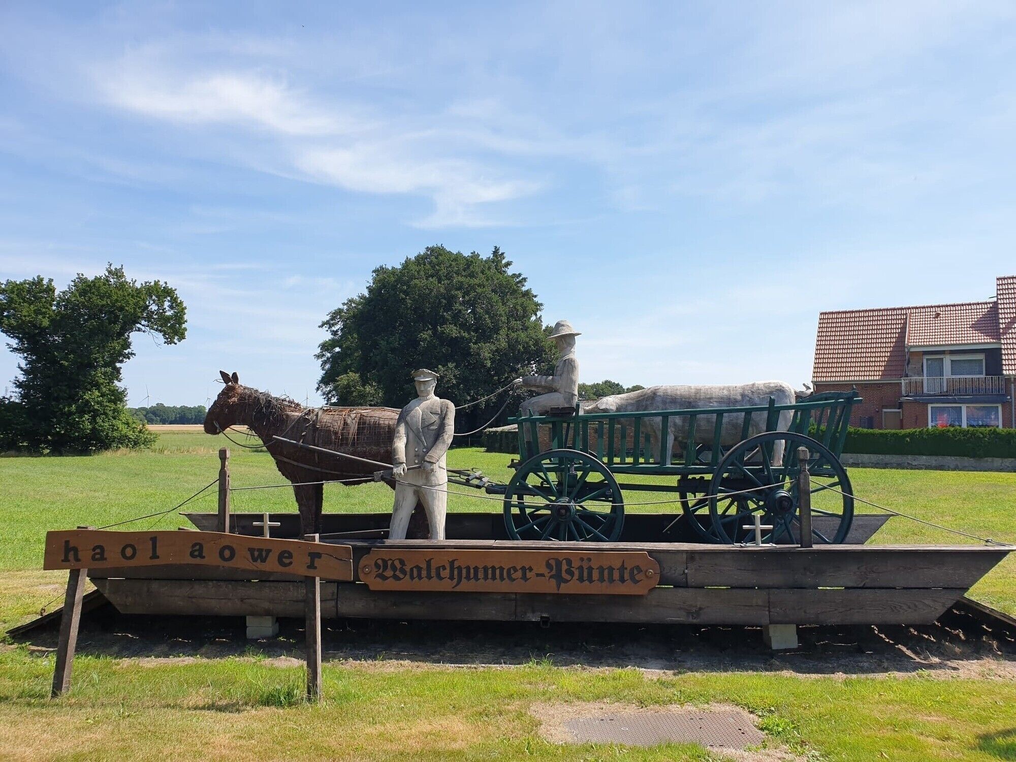 A historical exhibit with a statue, a horse-drawn carriage, and a sign reading 'haolower Walschumer-Binne.'