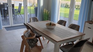 A dining area with a table, chairs, and a view through large glass doors to an outdoor patio.