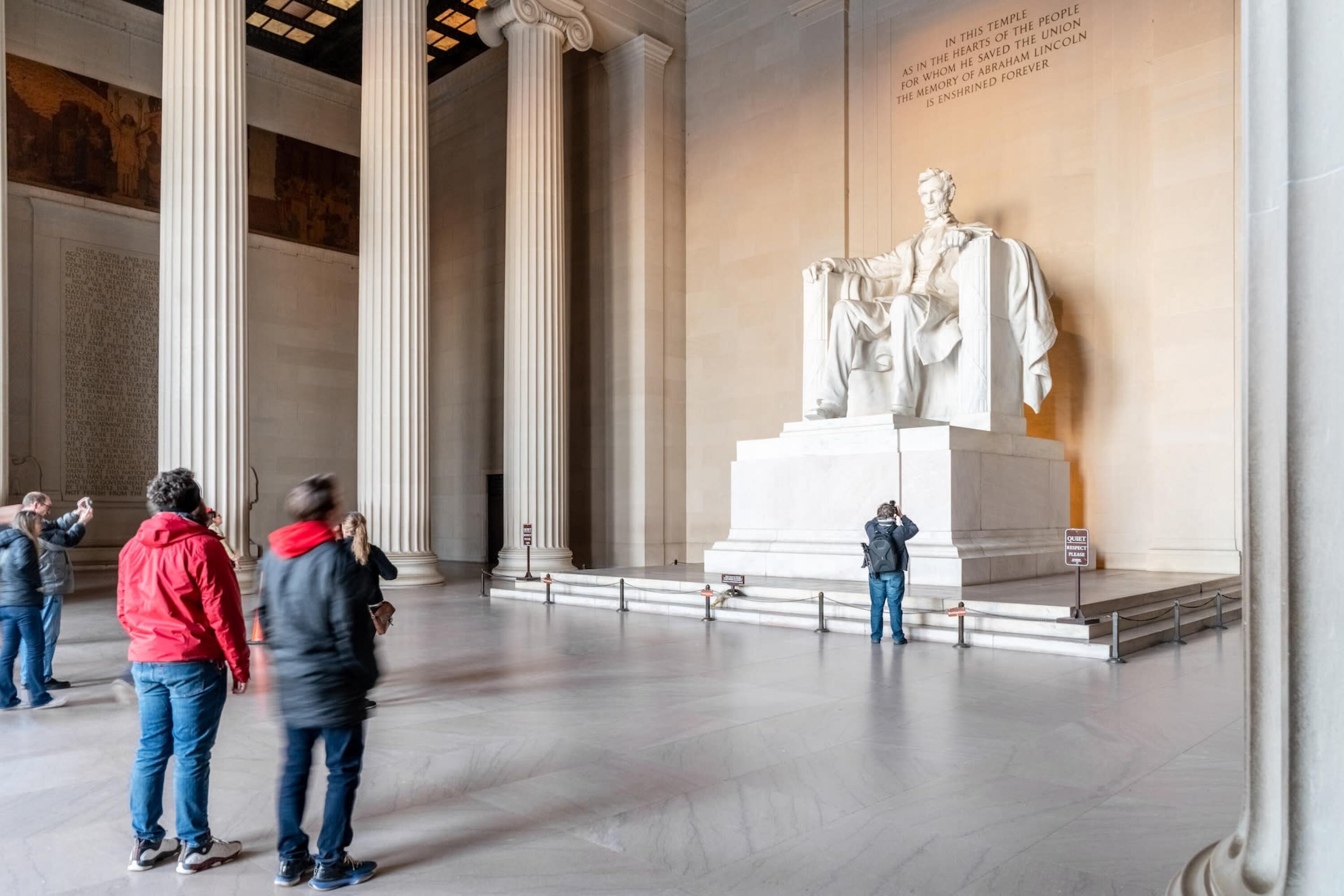 A large white statue in a spacious hall with high ceilings and columns.