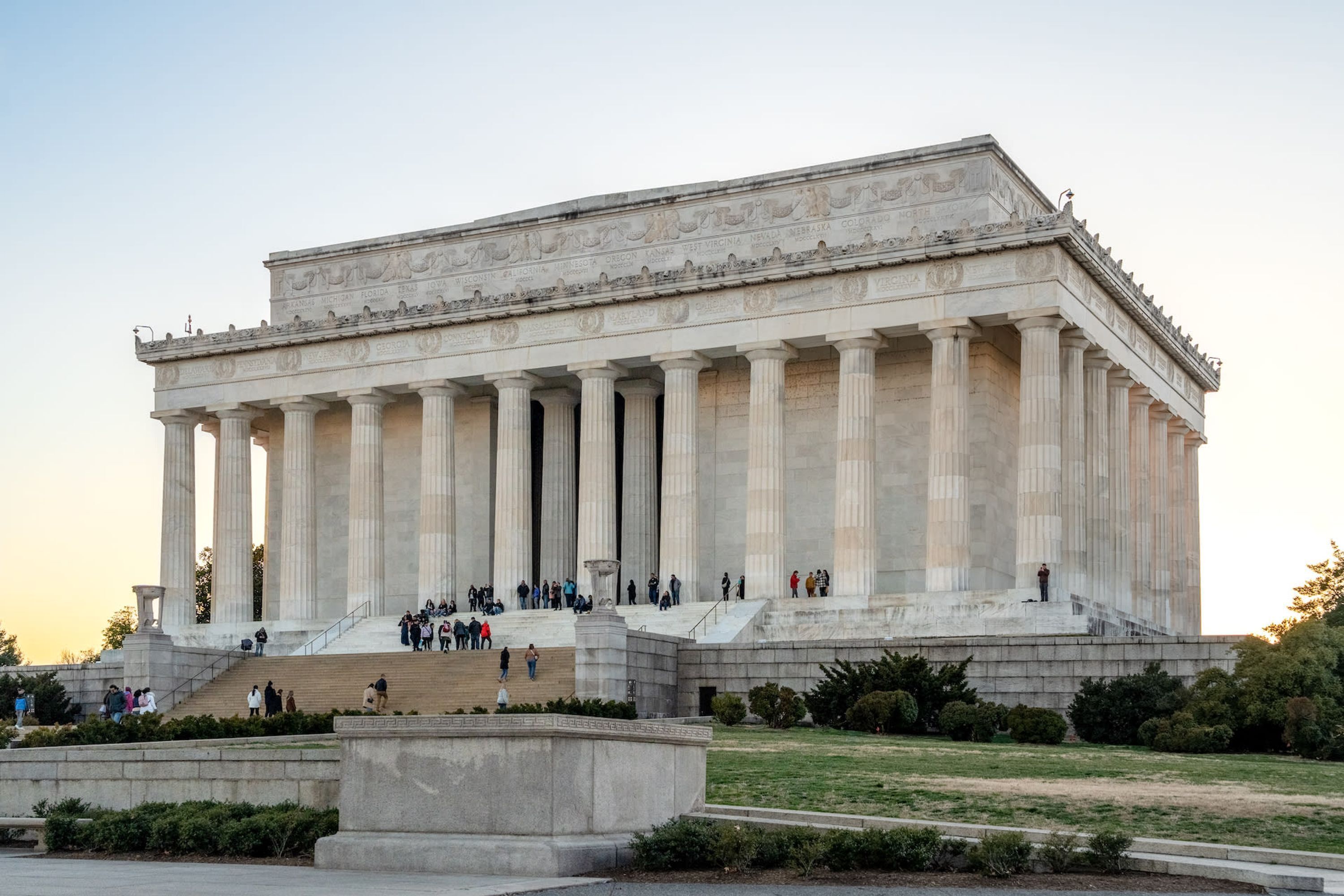 A large neoclassical building with a grand staircase and columns, surrounded by a landscaped area.