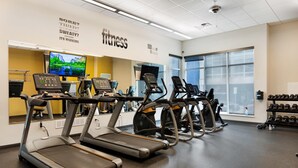 A fitness center with treadmills, exercise bikes, and dumbbells.