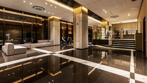 Eine moderne Lobby mit poliertem Marmorboden, Sitzbereichen und einer Treppe zu den oberen Stockwerken.