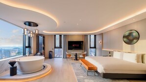 Ein modernes Hotelzimmer mit einem großen Bett, einer Badewanne, einem Fernseher und Blick auf die Stadt.