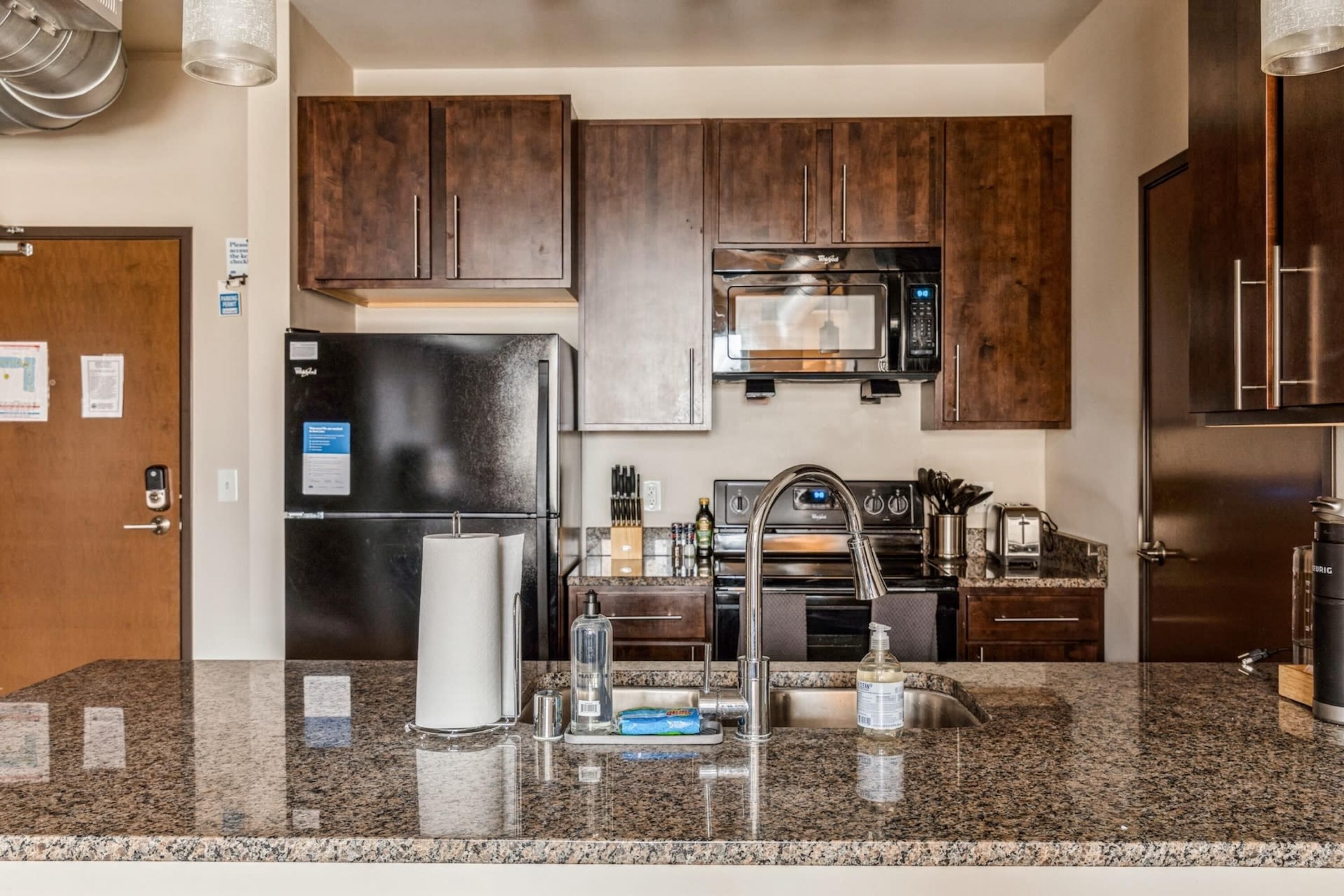 A modern kitchen with dark wooden cabinets, stainless steel appliances, and granite countertops.