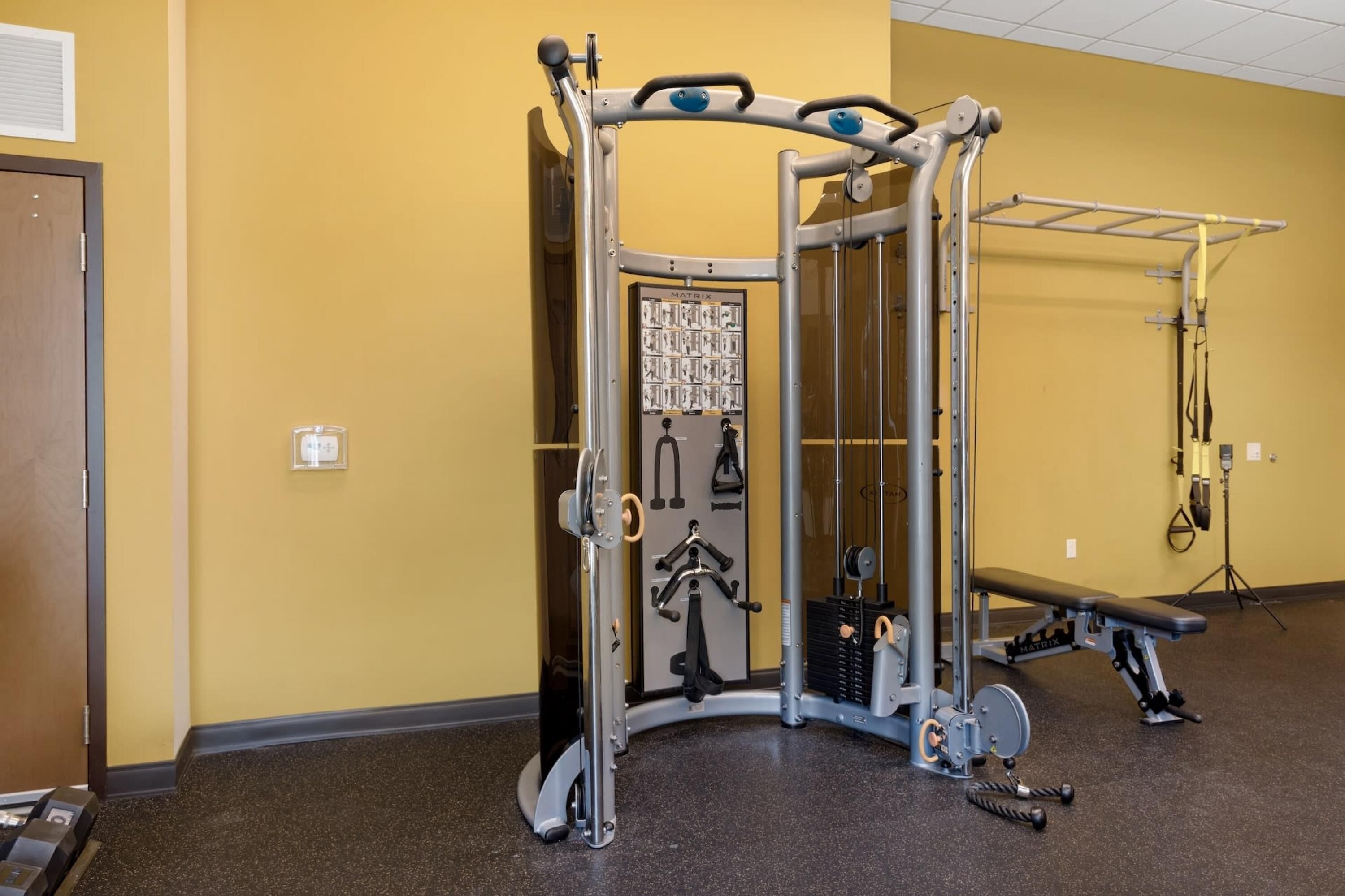 Un gimnasio con una jaula para sentadillas, banca y diverso equipo de ejercicio.