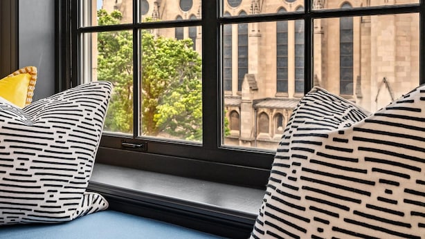 A window seat with patterned cushions, overlooking a historic building with multiple towers and arched windows.