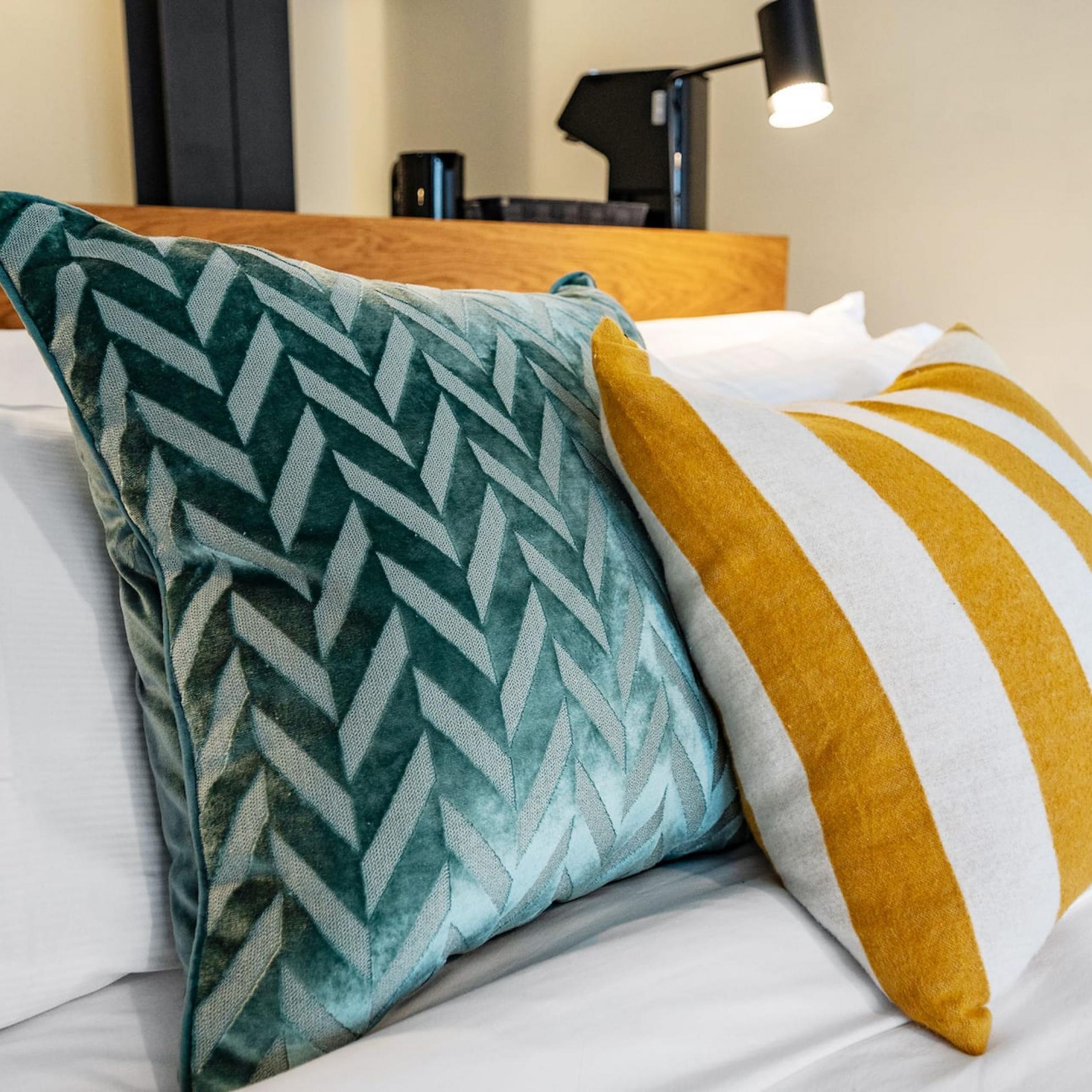 A bed with two pillows, one with a chevron pattern and the other with yellow stripes.