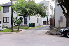 Rua residencial com casas, uma árvore e um carro estacionado.