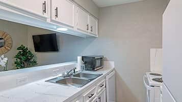 Una cocina moderna con armarios blancos, encimera de mármol, microondas, estufa y fregadero.