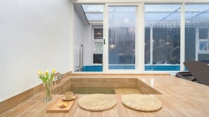 Ein modernes Badezimmer mit einer Duschkabine, einer Badewanne und einer Sitzecke mit Stuhl und Tisch.