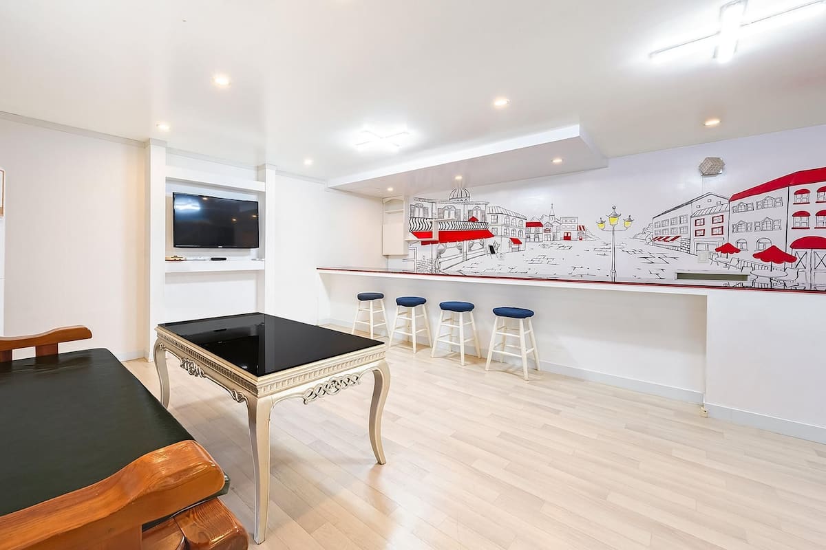 A modern kitchen with a bar area, a dining table, and a TV mounted on the wall.