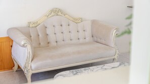 A cream-colored sofa with a tufted backrest and ornate detailing, positioned in a room with a marble floor and a wooden cabinet. - Gyeongju Jullietapoolvilla&kidspension (Gyeongju)
