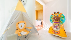 A tent with a bear design, a giraffe toy, and a bathroom with wooden walls.