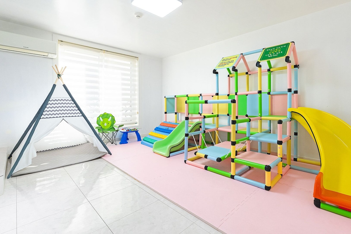 A play area with a slide, climbing structure, and a tent.