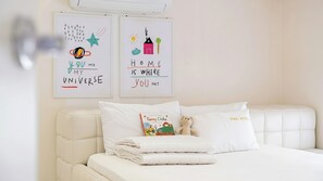 A bedroom with a white bed, a teddy bear, and two wall art pieces with motivational quotes.