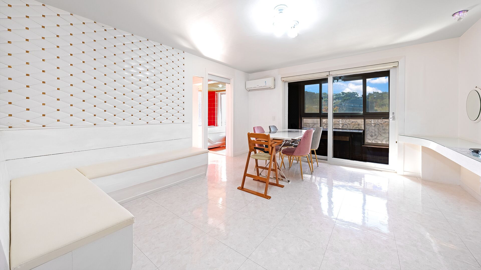 Un interno moderno con zona pranzo, parete bianca con motivo geometrico e una grande finestra vista.