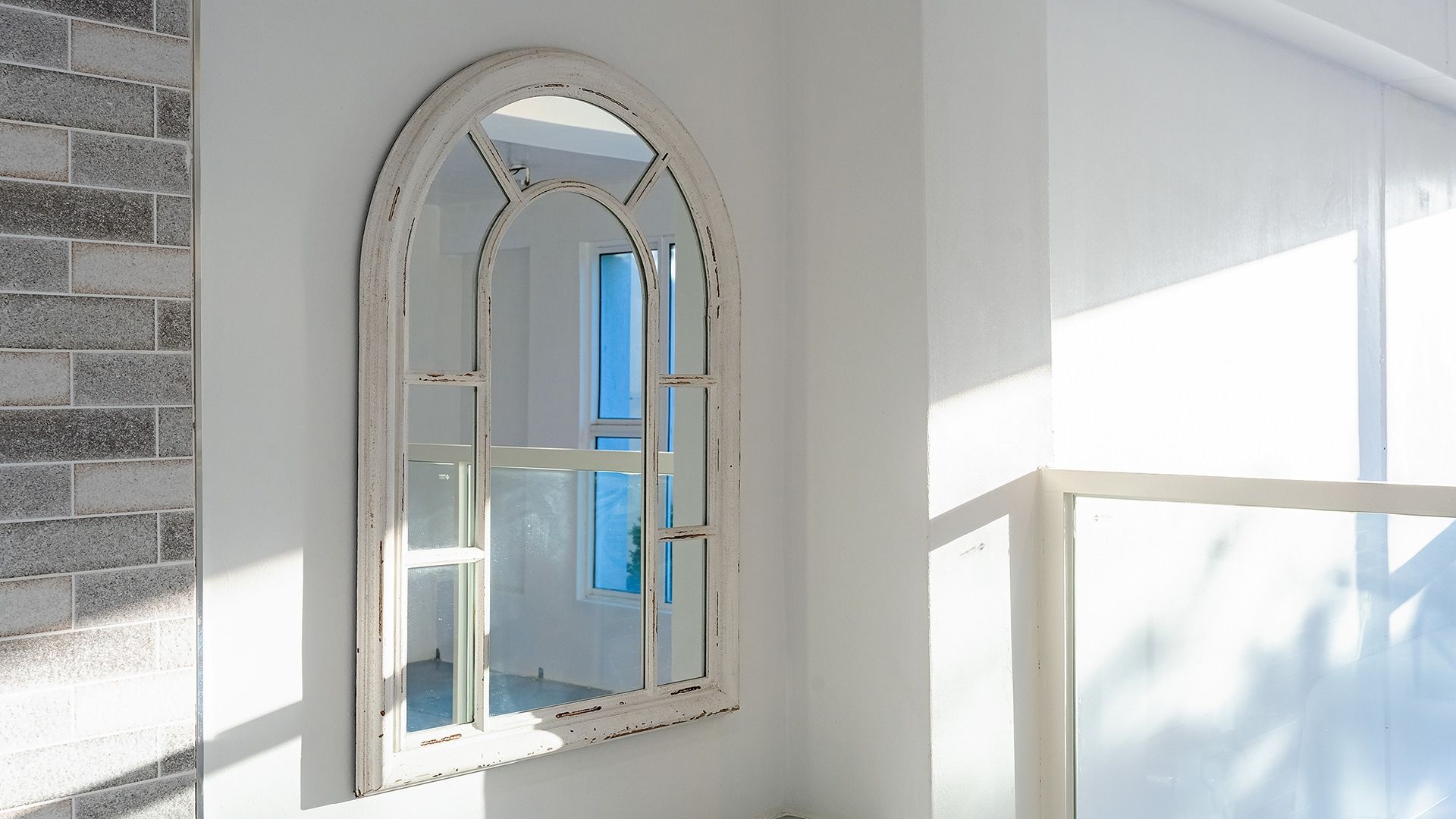 Una habitació amb una paret blanca, una finestra amb marc blanc i vista al cel blau.