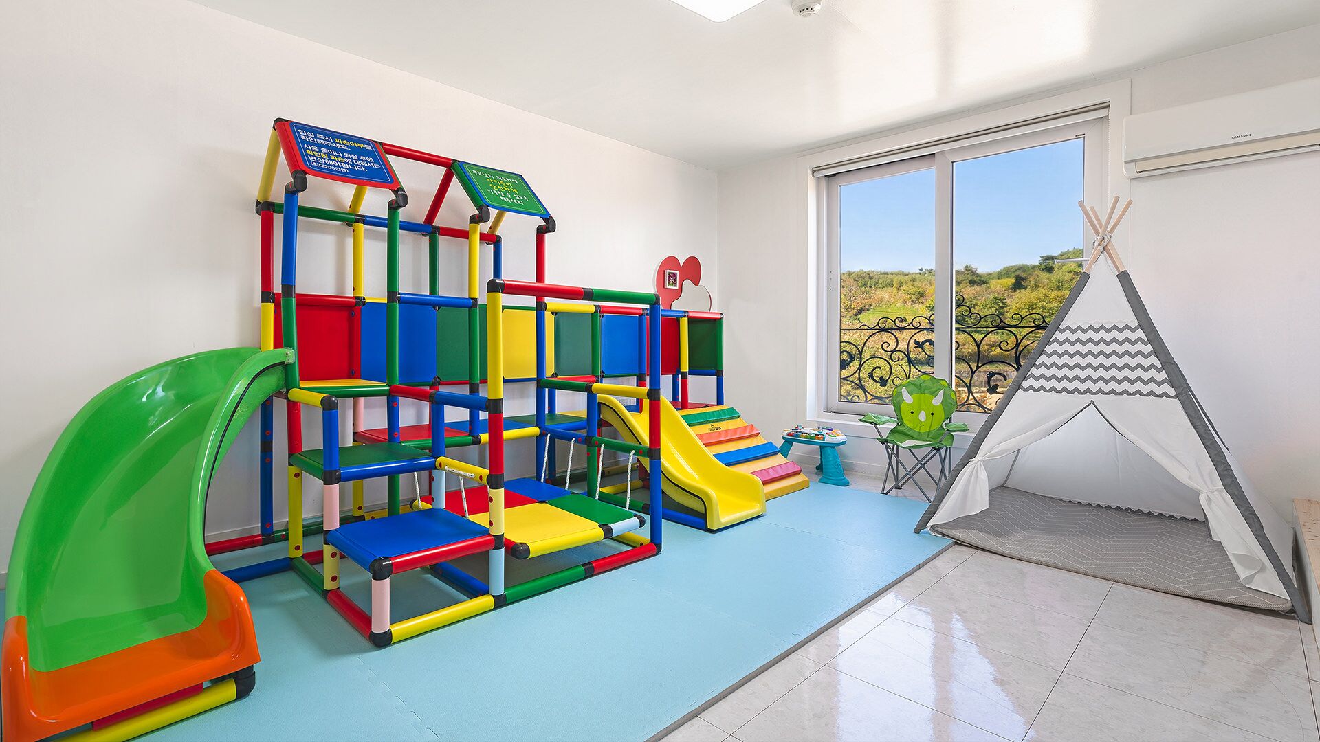 Zona de juegos con estructura para escalar, tobogán y tipi.