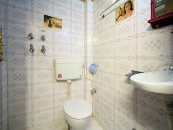 Bathroom features a toilet, sink, and mirror, with a patterned wallpaper and towel rack.