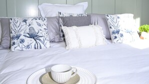 A neatly made bed with a cup and saucer, surrounded by various pillows and a small potted plant. - Holbrook Hotel (Holbrook)
