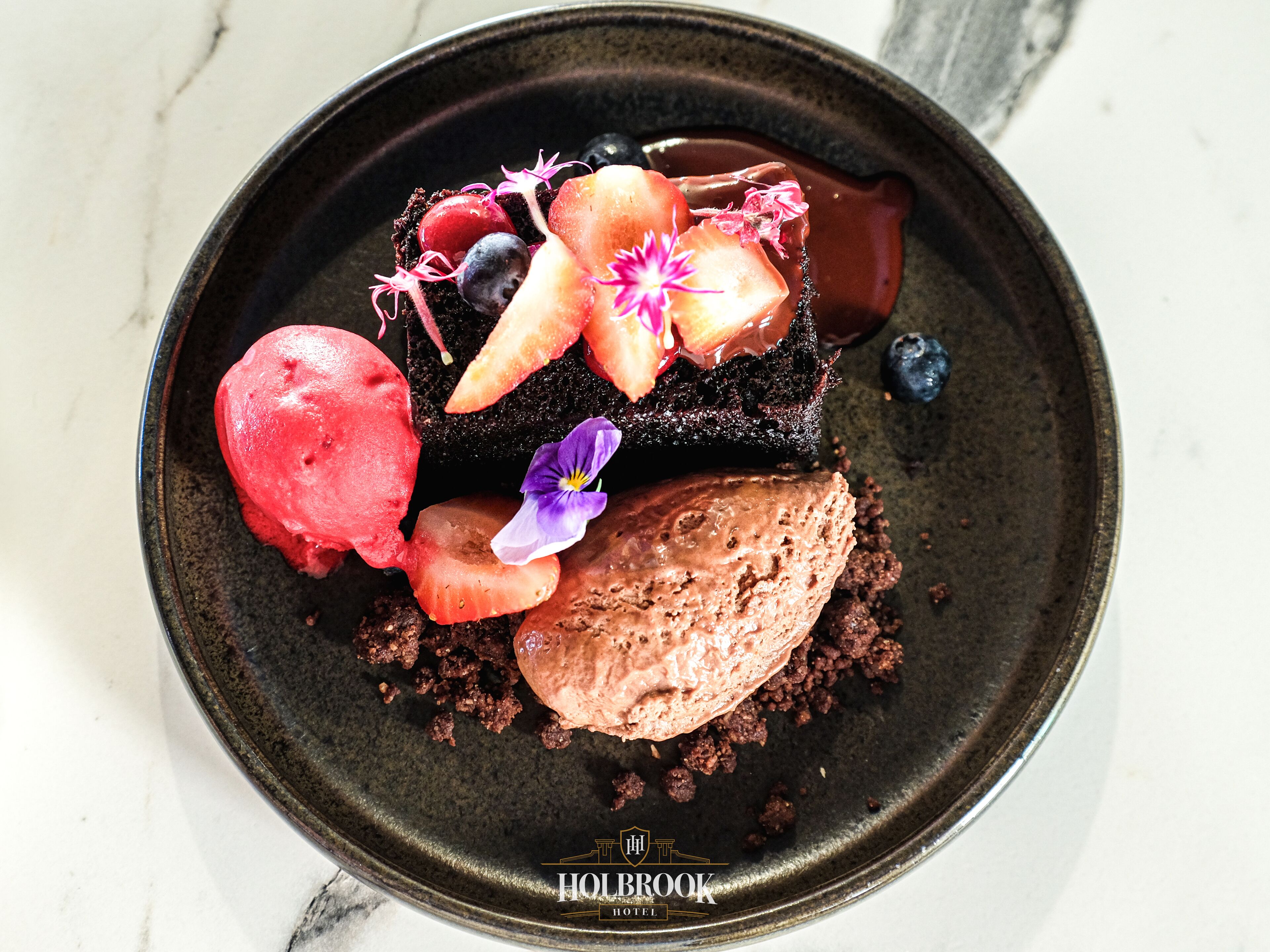 A dessert on a dark plate with a marble background.