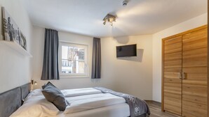 Ein Schlafzimmer mit einem Bett, einem an der Wand montierten Fernseher und einem Holzschrank.