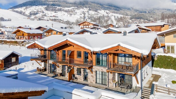 Eine schneebedeckte Lodge mit mehreren Holzhütten, großen Fenstern und Balkonen.