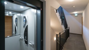 Ein moderner Aufzug mit digitaler Steuerung, Glastür und Holzverkleidung.