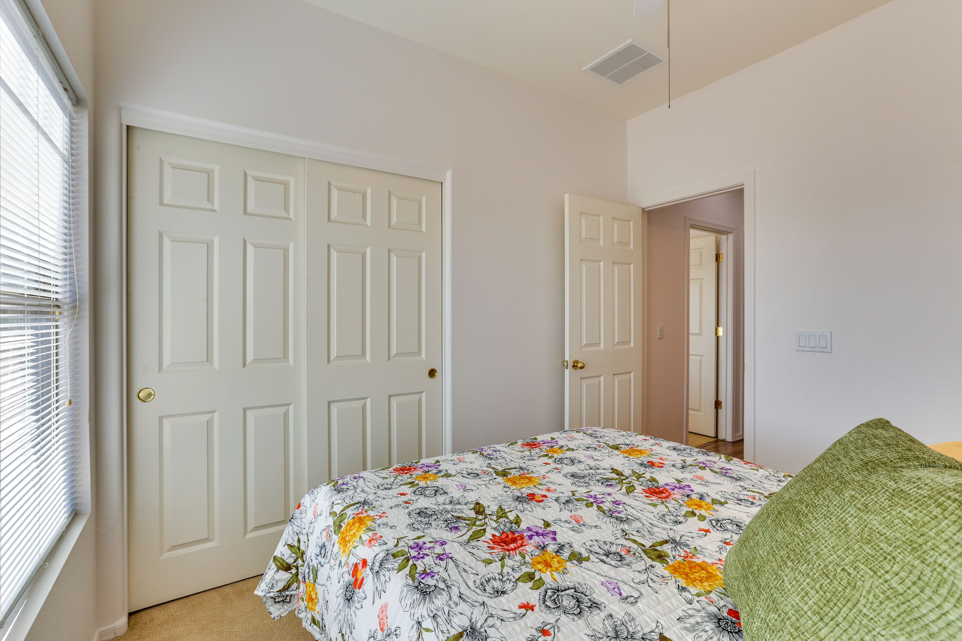 Una camera da letto con una coperta dal motivo floreale, una poltrona verde e una porta bianca.