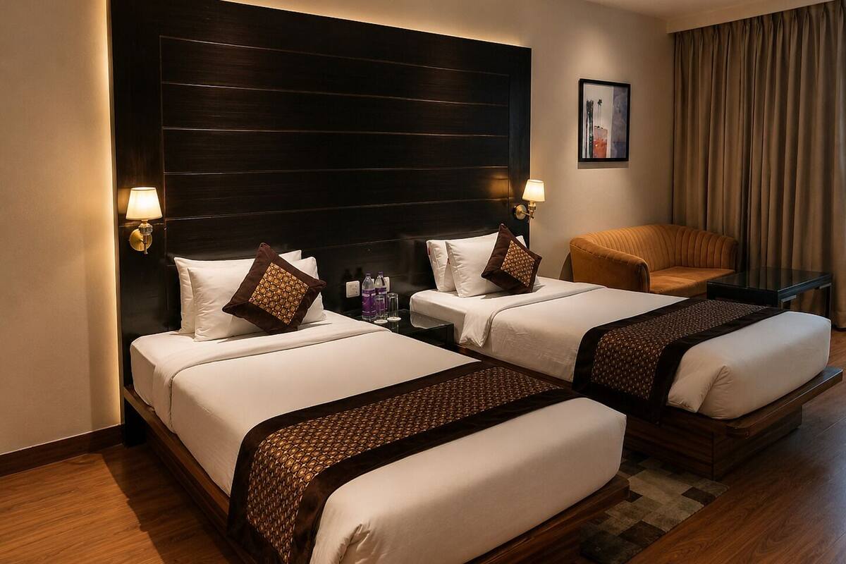 A hotel room with two beds, a sofa, a lamp, and a painting on the wall.