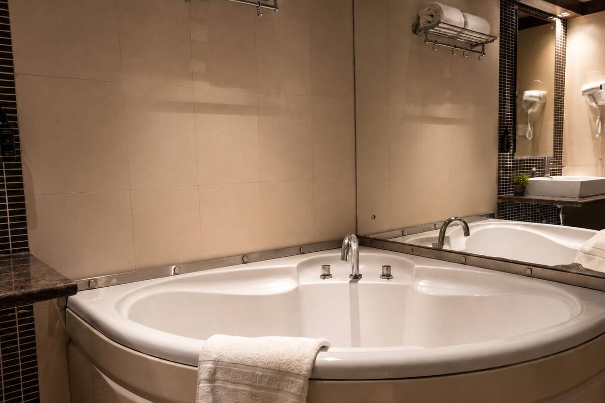 A bathroom with a large bathtub, a mirror, a towel rack, and a sink.
