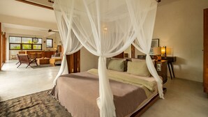 A spacious bedroom with a large bed, a ceiling fan, and a view of the living area. - Nowhere Villa (Pecatu)